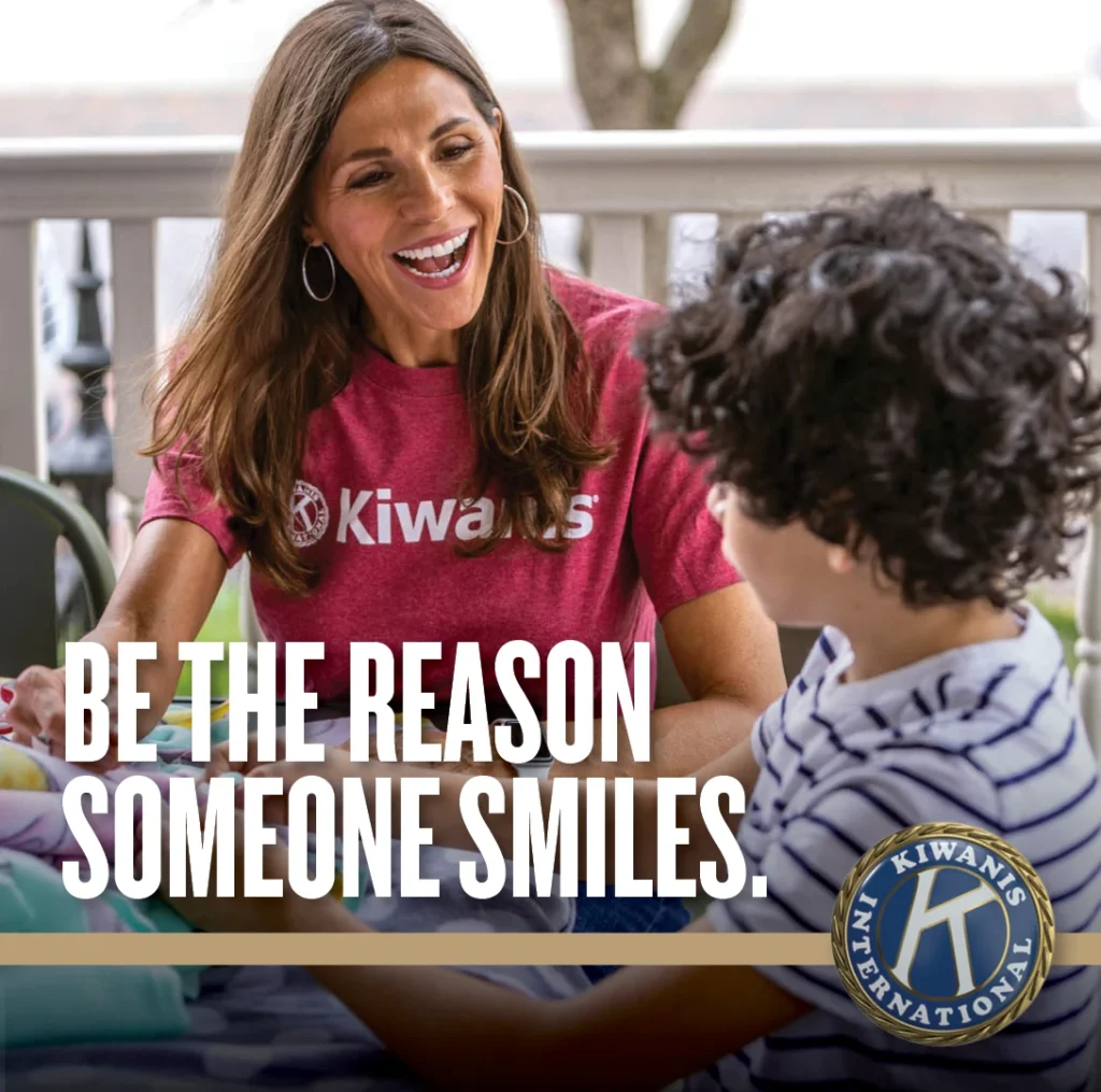 Kiwanis volunteer and child with the message: Be the reason someone smiles.
